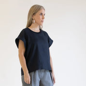 Woman wearing a black top and gray pants against a white background