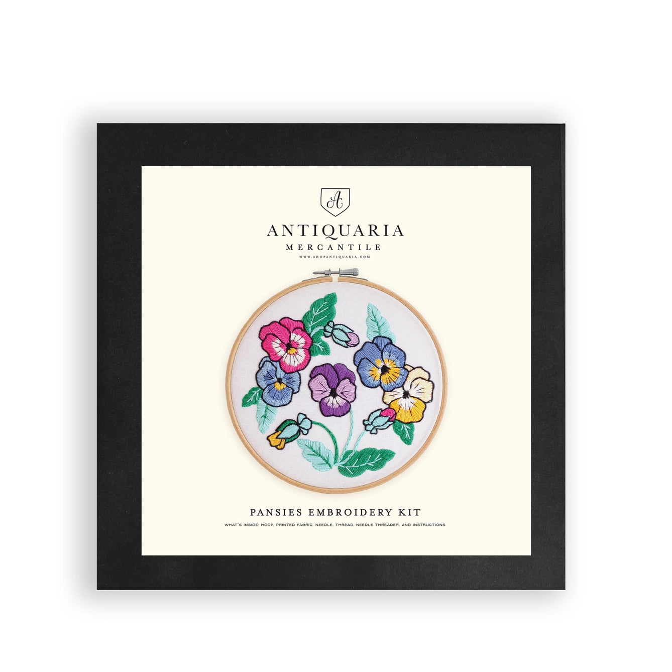 Embroidery kit packaging with pansies design and Antiquaria Mercantile branding.