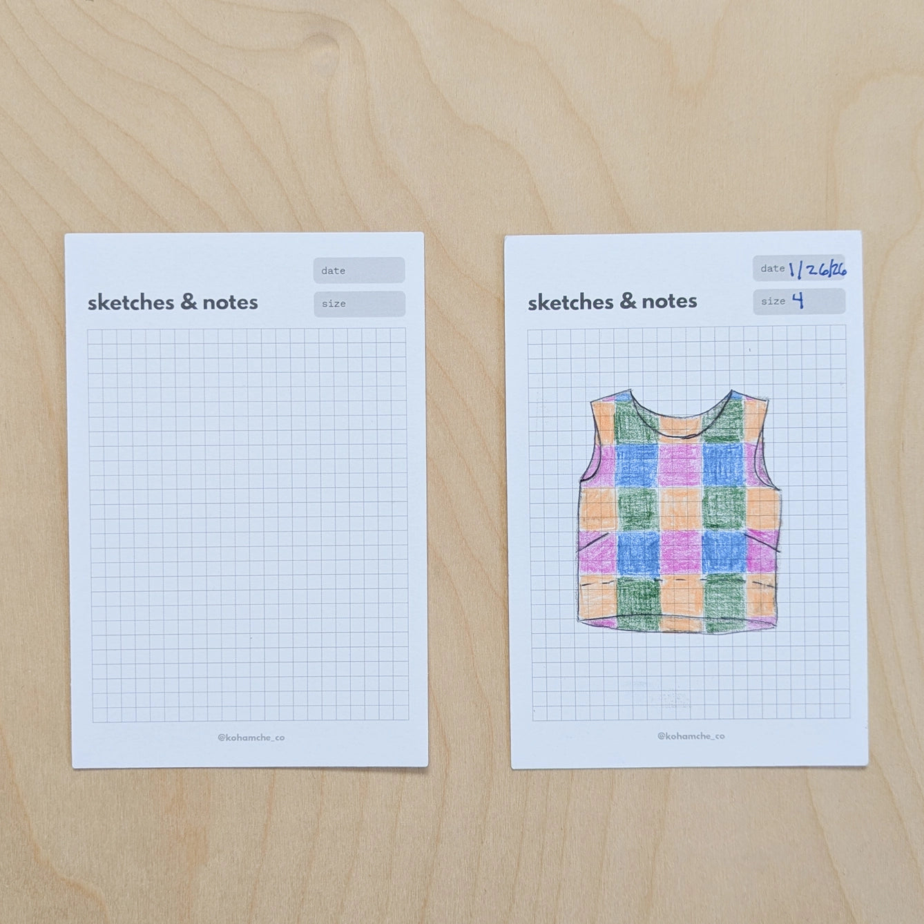 Two sheets of paper with grid and drawing on a wooden surface
