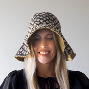 person wearing a patterned sun hat against a plain background