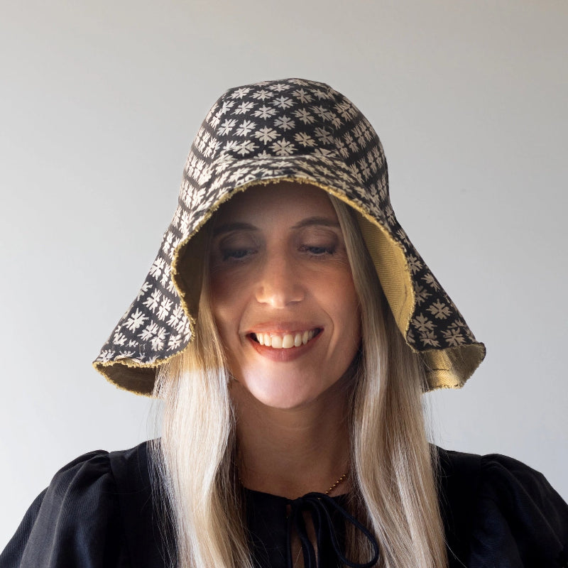 person wearing a patterned sun hat against a plain background