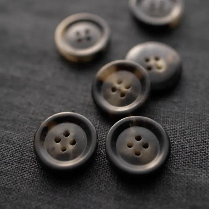 Six brown buttons on a textured black surface