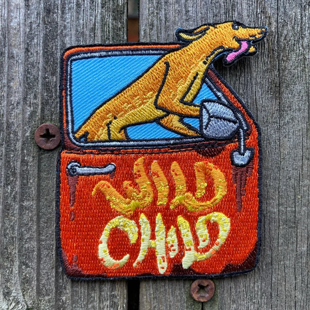 Embroidered patch with a dog and 'Wild Child' text on a wooden background