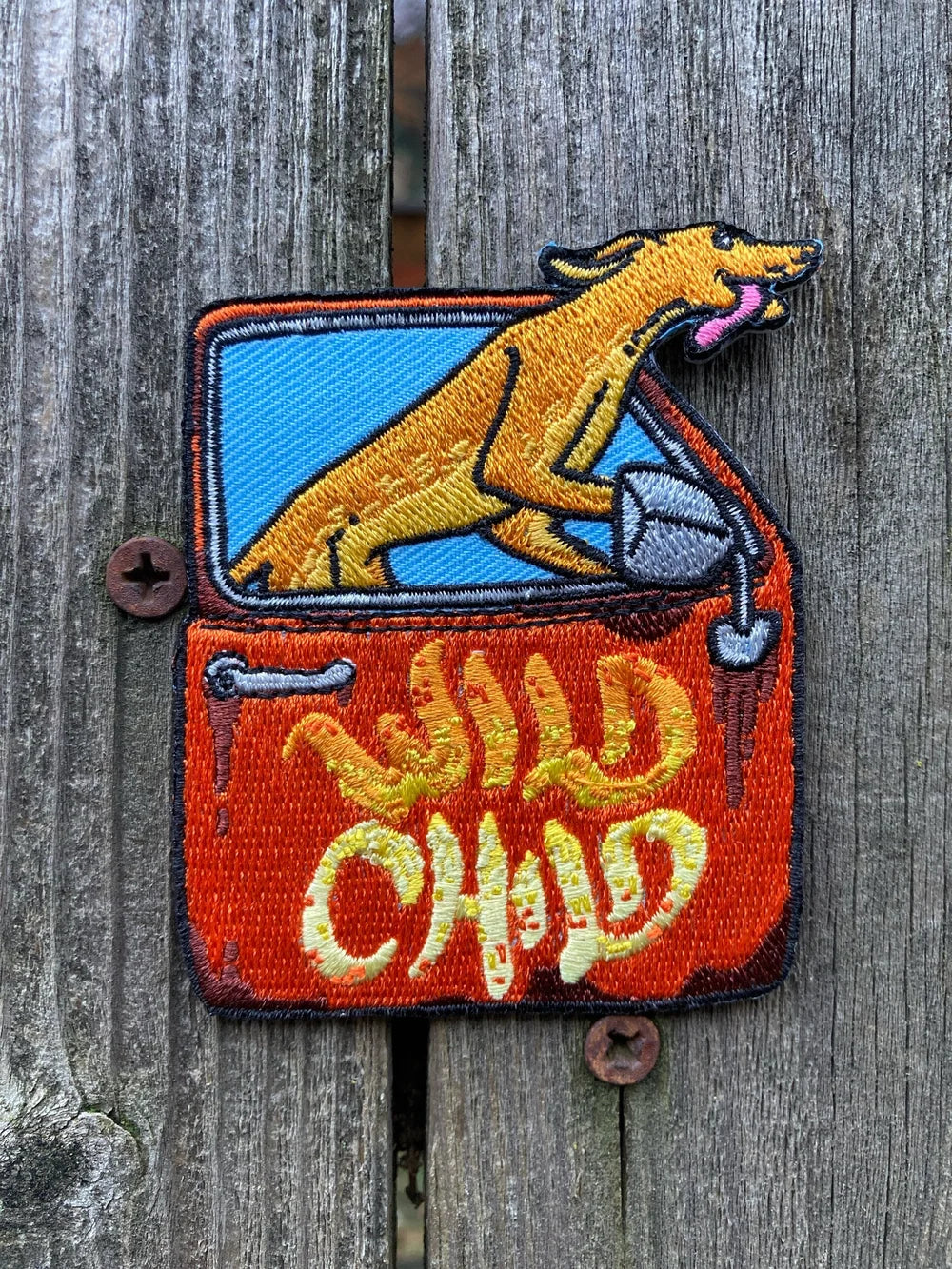 Embroidered patch with a dog and 'Wild Child' text on a wooden background