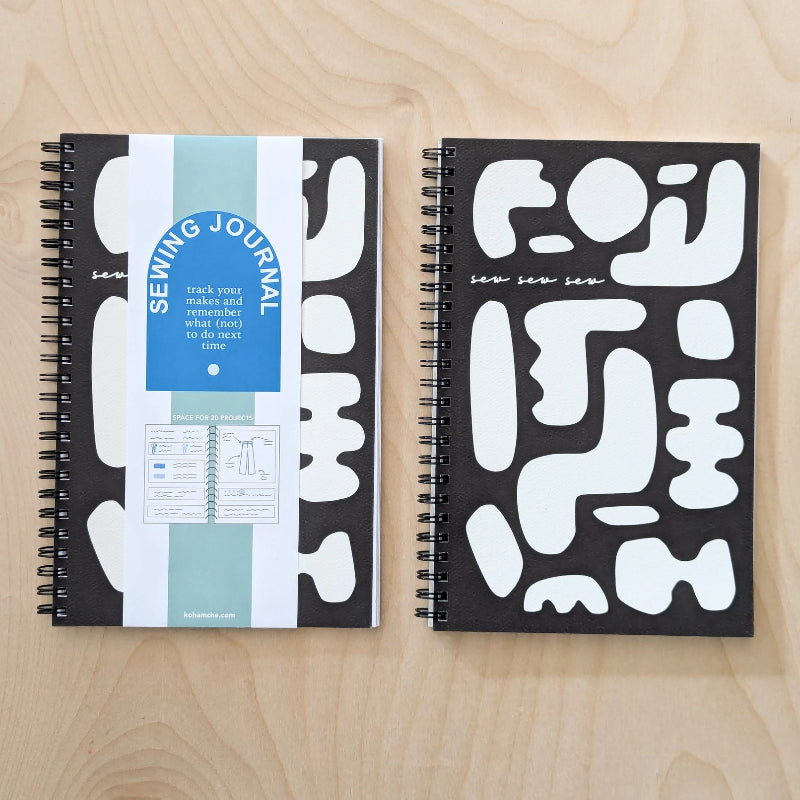 Two spiral-bound notebooks with abstract white patterns on a wooden surface