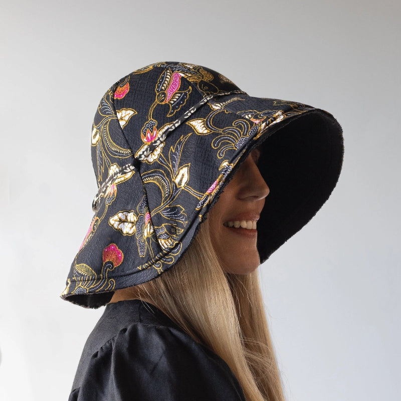 person wearing a black floral-patterned bucket hat on a light gray background