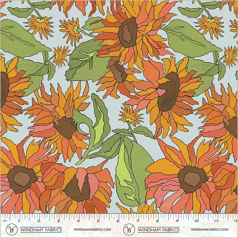 Fabric swatch of large orange and red sunflowers on a light blue background.