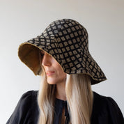 person wearing a patterned bucket hat against a plain background