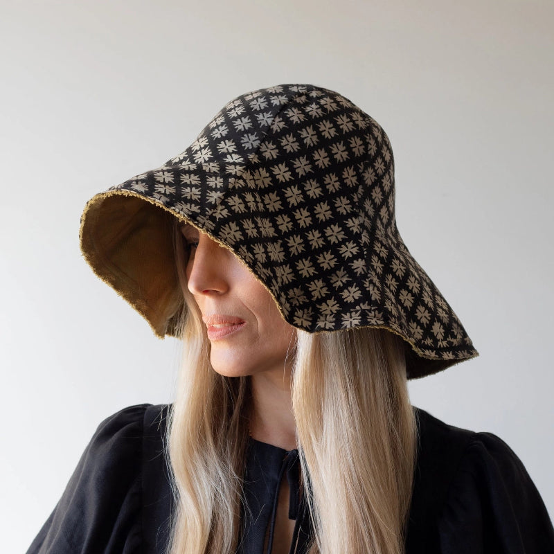 person wearing a patterned bucket hat against a plain background