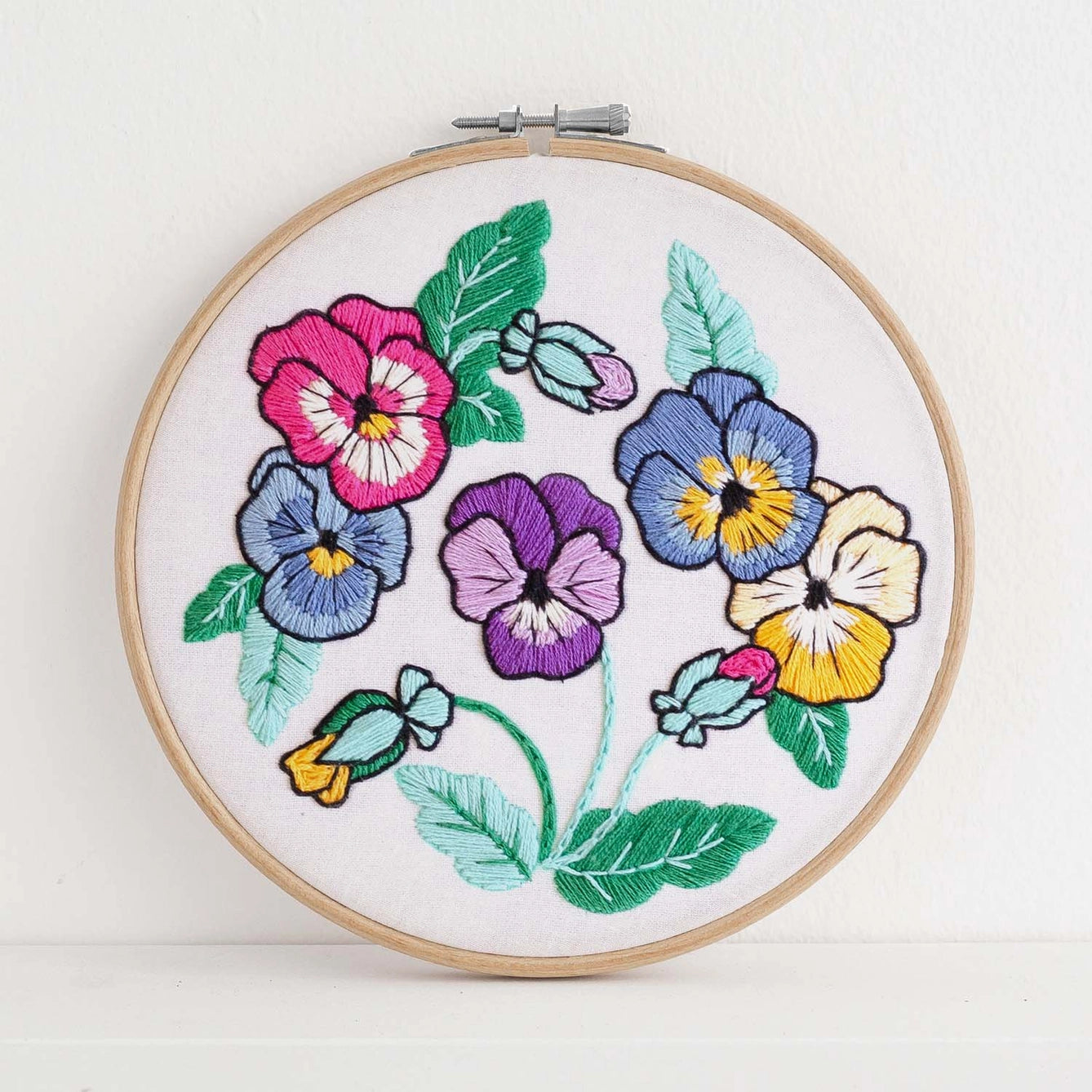Embroidery hoop with colorful floral design on a white background
