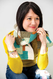 Woman wearing a colorful patchwork scarf with a plain background