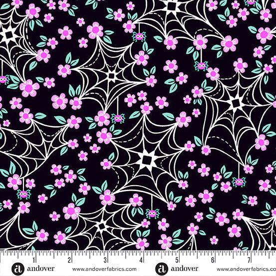 Fabric pattern with spider webs and pink flowers on a black background, featuring a ruler for scale.