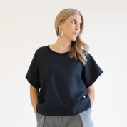 Woman wearing a black oversized sweater against a plain background