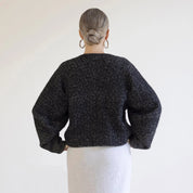 Person wearing a black textured sweater against a white background