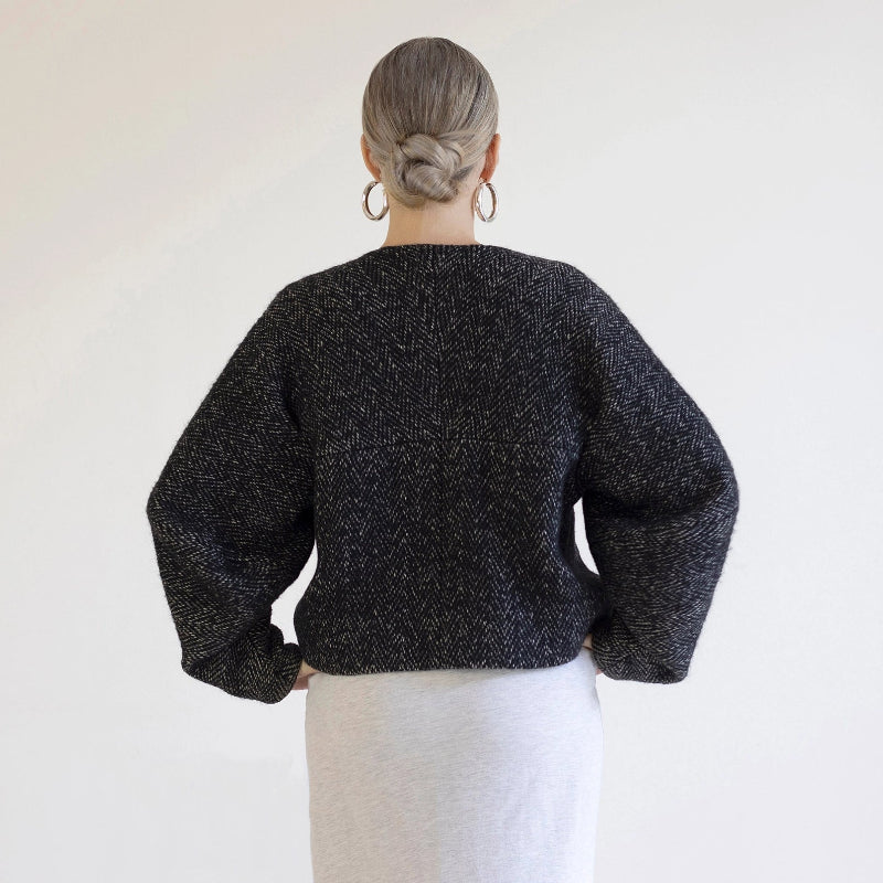 Person wearing a black textured sweater against a white background