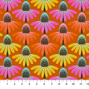 Fabric with pattern of colorful flowers on a rust orange background with a ruler at the bottom for scale.