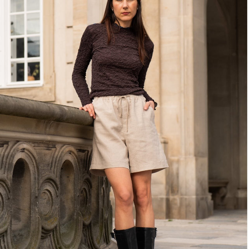 Person standing outdoors in front of a stone building