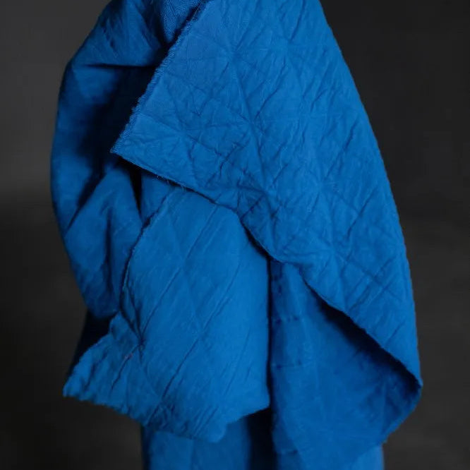 Blue quilted blanket on a dark background