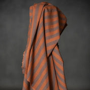 Striped fabric with orange and gray pattern draped over a dark background