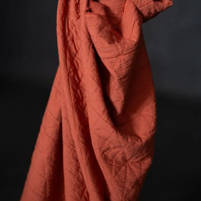 Folded terracotta-colored fabric against a black background