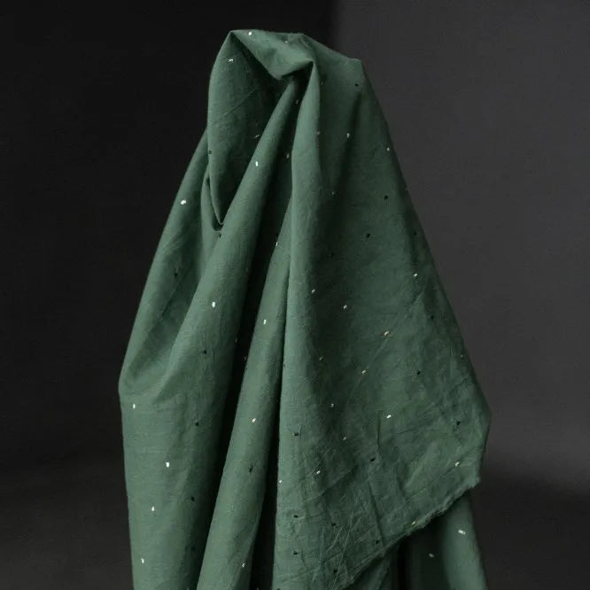 Dark green fabric with small white dots on a dark background