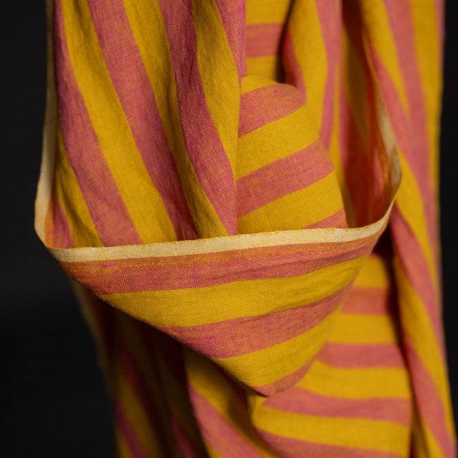 Close-up of a yellow and pink striped linen fabric with a dark background