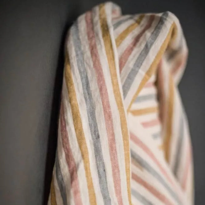 Striped fabric with multicolor pattern draped over a dark background