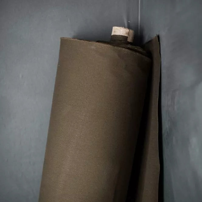 Roll of olive oilskin fabric against a gray wall