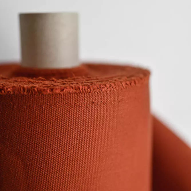 Roll of rust colored fabric on a white background