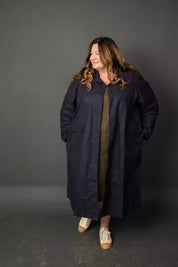 Woman wearing a long dark coat against a gray background