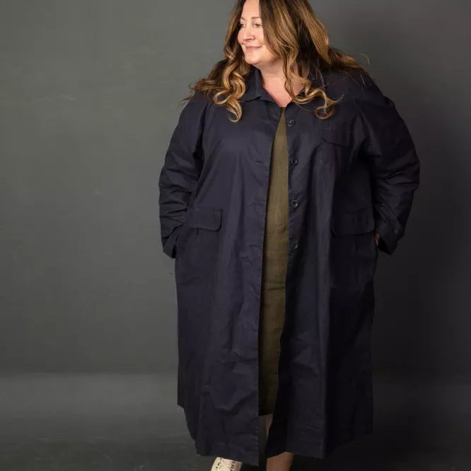 Woman wearing a long dark coat against a gray background