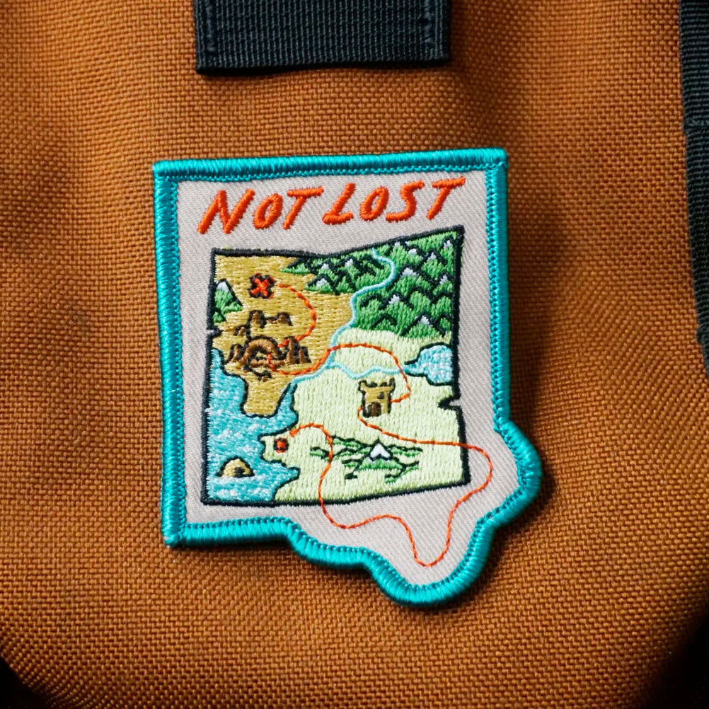 Patch on a brown bag with 'Not Lost' text and map design