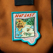 Patch on a brown bag with 'Not Lost' text and map design