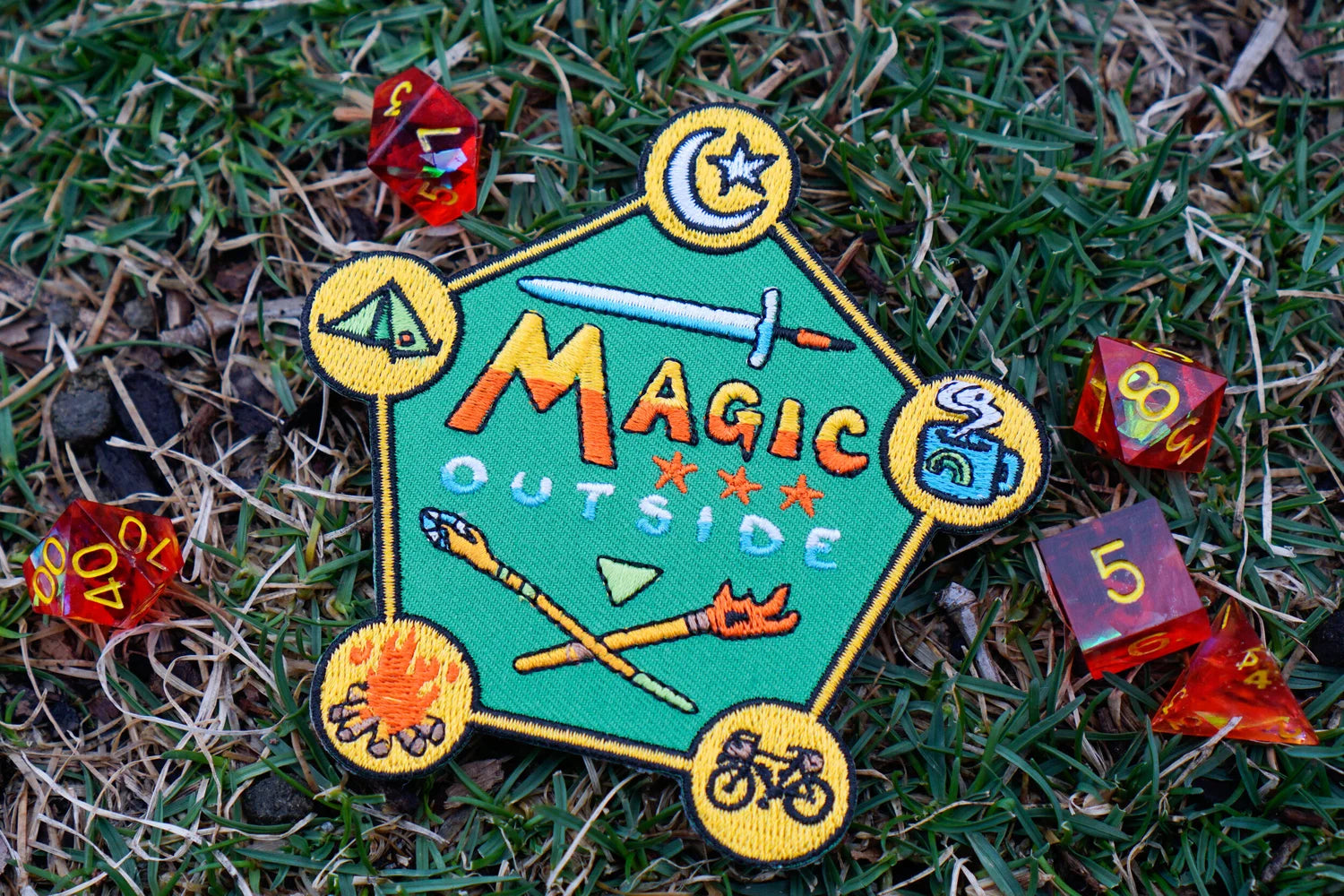 Colorful 'Magic Outside' patch on grass with dice around