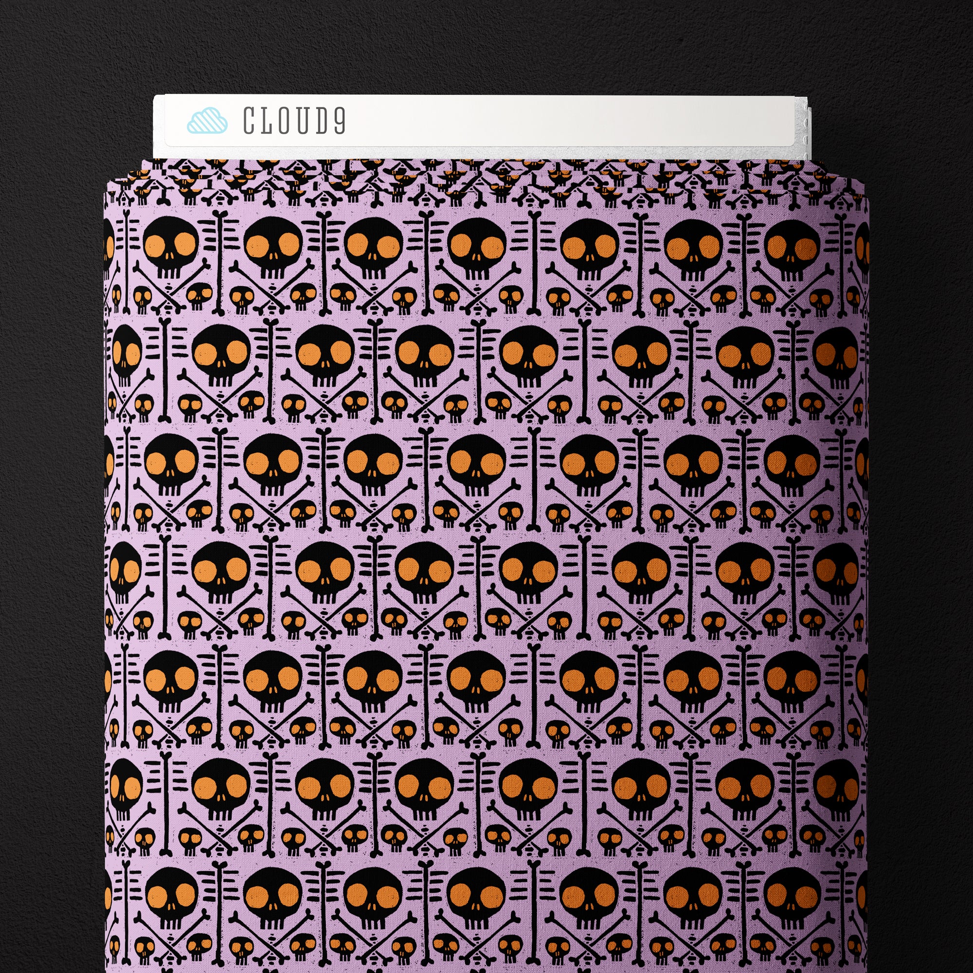 Fabric with light purple background and black skulls with orange eye sockets.