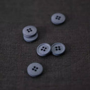 Set of gray buttons on a textured brown fabric background
