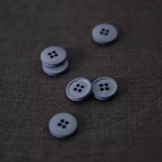 Set of gray buttons on a textured brown fabric background