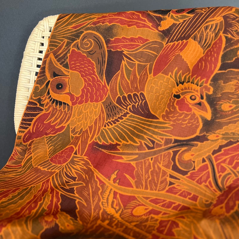 Rust toned fabric with intricate parrot pattern on a dark background