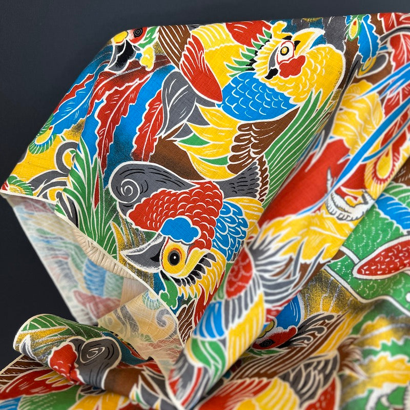 Colorful fabric with bird pattern against a dark background.