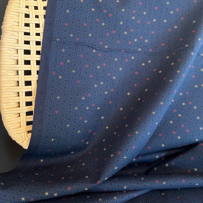 Navy fabric with small geometric pattern draped over a woven basket