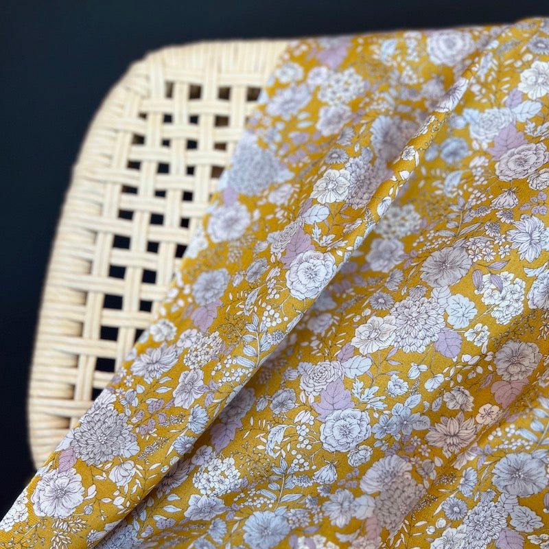 Floral fabric with yellow background draped over a wicker chair.