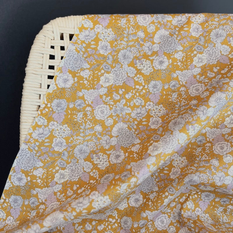 Floral patterned fabric draped over a wicker chair on a black background