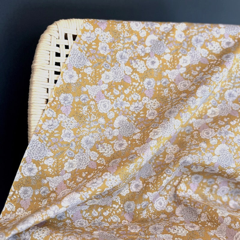 Floral patterned fabric draped over a wicker chair against a dark background