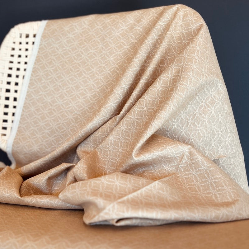 Beige textured fabric draped over a chair against a dark background