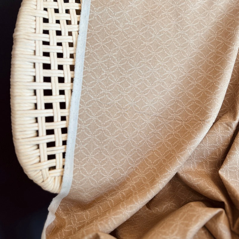 Close-up of a textured beige fabric on a woven wicker chair corner.