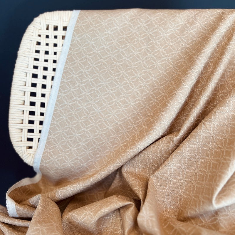 Beige textured fabric draped over a wicker chair against a dark background
