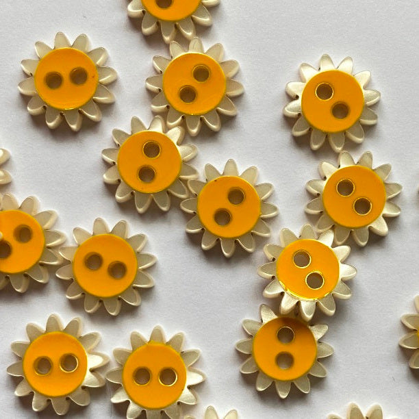 Sunflower-shaped buttons with yellow centers and beige petals on a white background