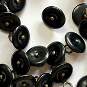 Close-up of black buttons with gold centers on a white background