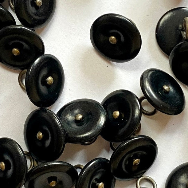 Close-up of black buttons with gold centers on a white background