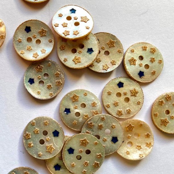Gold buttons with star and circle patterns on a white background